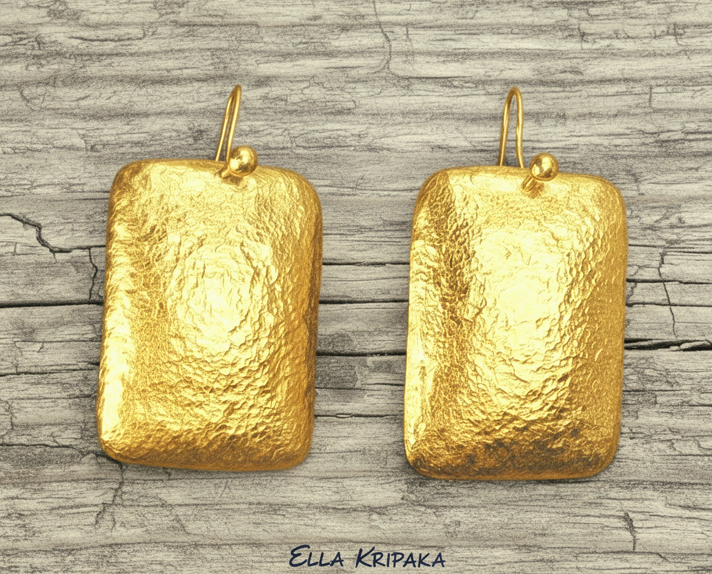 Hammered 24k gold, pure 9999 gold convex rectangular earrings with shiny forged gold textures on old wooden surface, artist-jeweler 'Ella Kripaka' branding