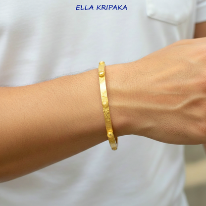 24k gold hammered bangle textured bracelet with convex rounds is worn by a man on wrist and on white t-shirt background, artist 'Ella Kripaka' branding