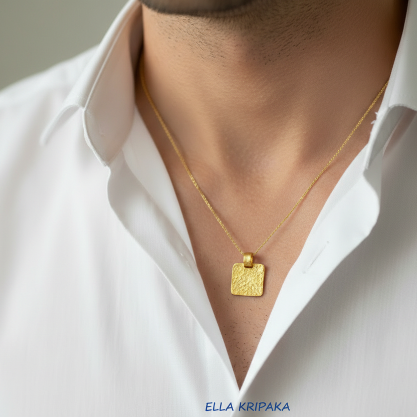 Hammered 24k gold, pure 9999 gold square pendant on chain worn by a man and with white shirt and on grey background, artist-jeweler 'Ella Kripaka' branding