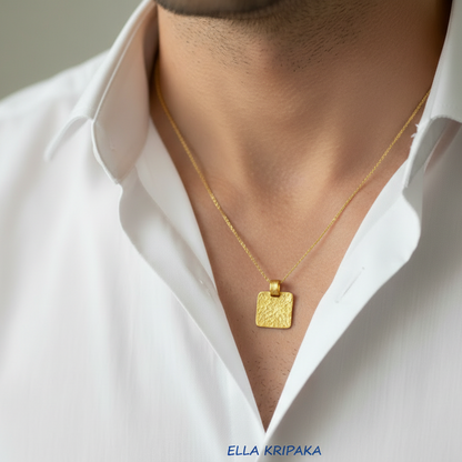 Hammered 24k gold, pure 9999 gold square pendant on chain worn by a man and with white shirt and on grey background, artist-jeweler 'Ella Kripaka' branding