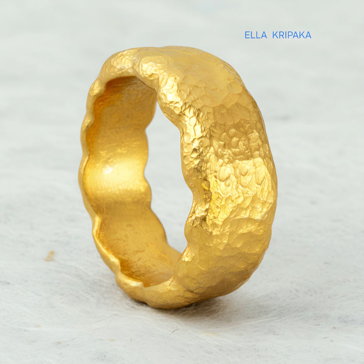 Hammered organic 24k Gold 9999 gold uneven wavy thick ring band with textured gold on a white craft paper background, branded 'Ella Kripaka'