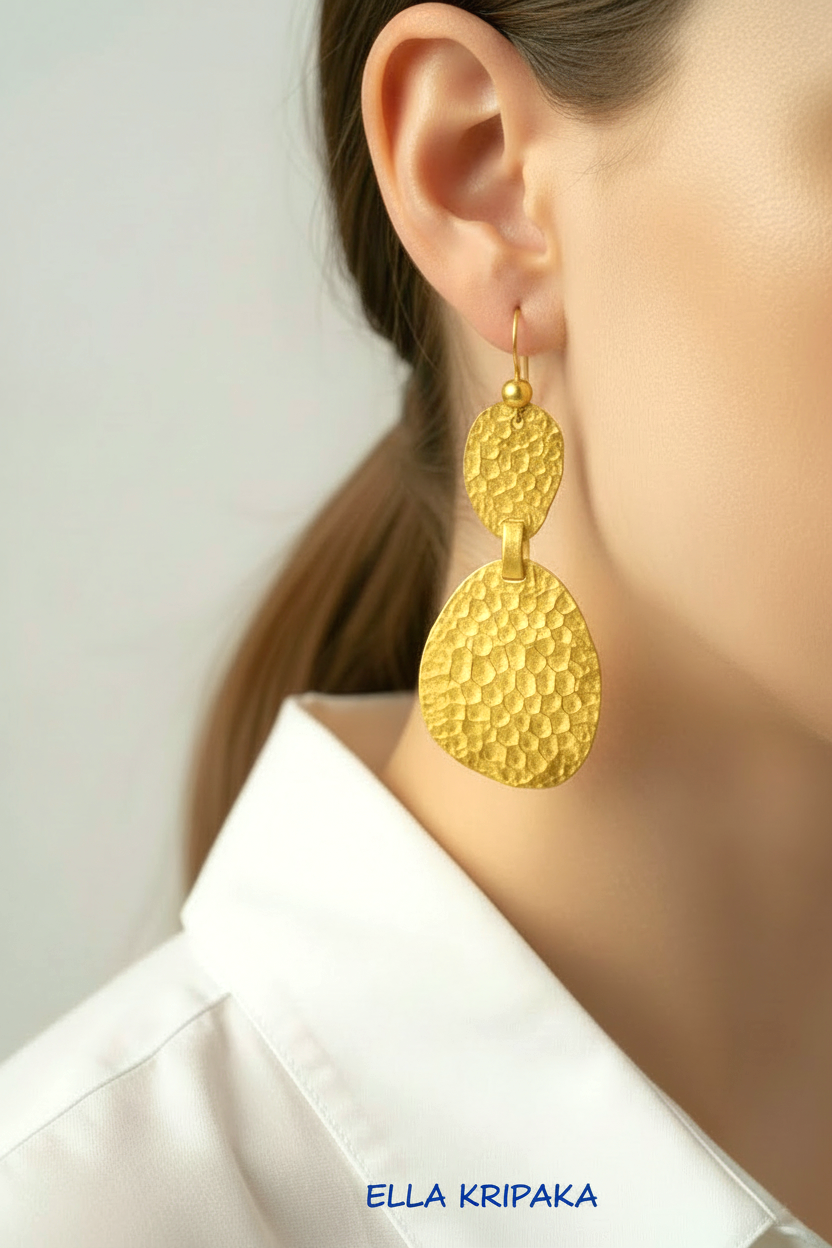 Hammered 24k 9999 gold organic uneven earrings worn by a model with a neutral background, branded 'Ella Kripaka'