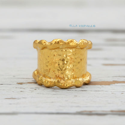 Organic hammered 24k 9999 Gold ring signet with uneven wavy thick edges on white old wooden surface, artist-jeweler's name 'Ella Kripaka' is written in picture