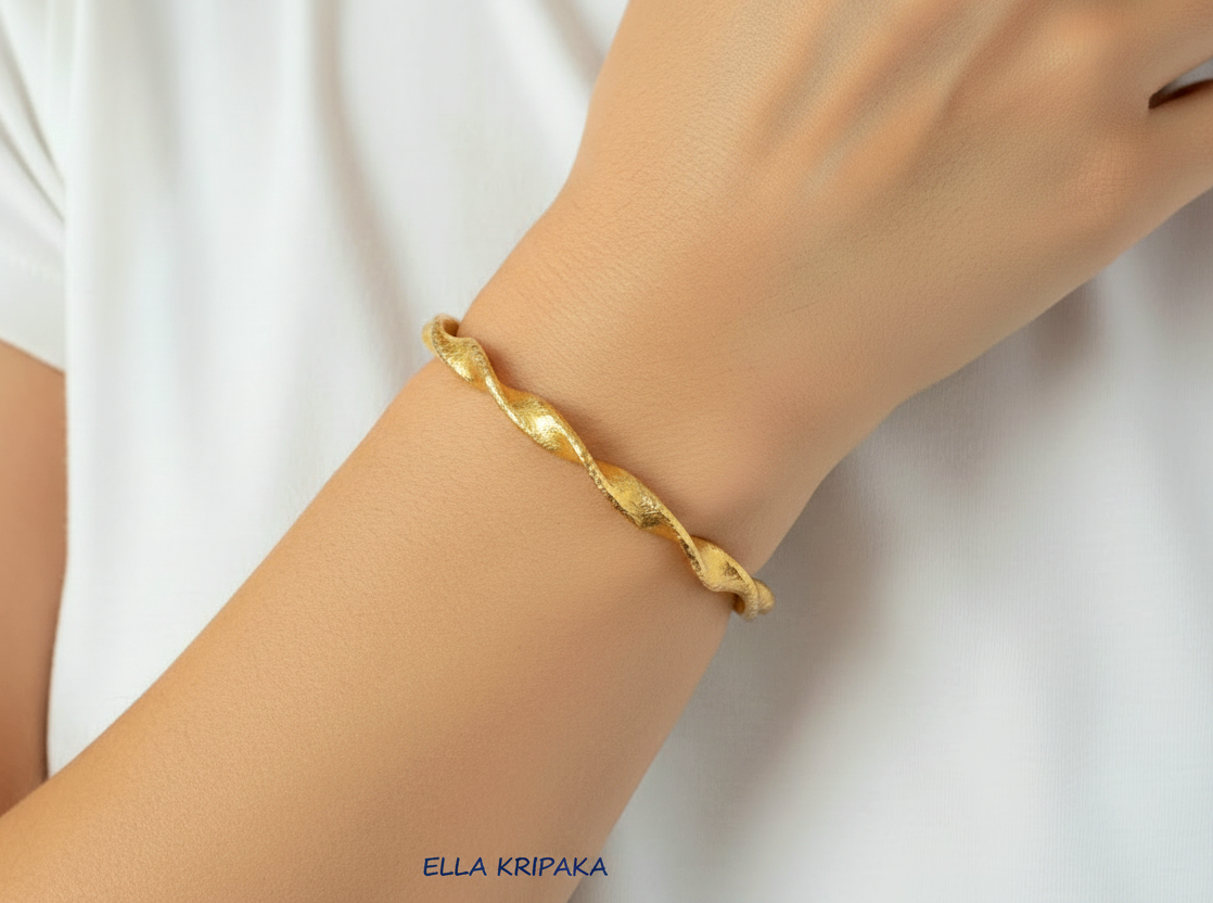 Twisted Viking hammered 24k 9999 gold bracelet cuff worn on wrist by a person and on a white background, branding artist-jeweler name 'Ella Kripaka'