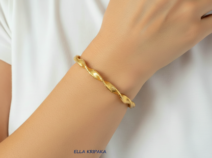 Twisted Viking hammered 24k 9999 gold bracelet cuff worn on wrist by a person and on a white background, branding artist-jeweler name 'Ella Kripaka'