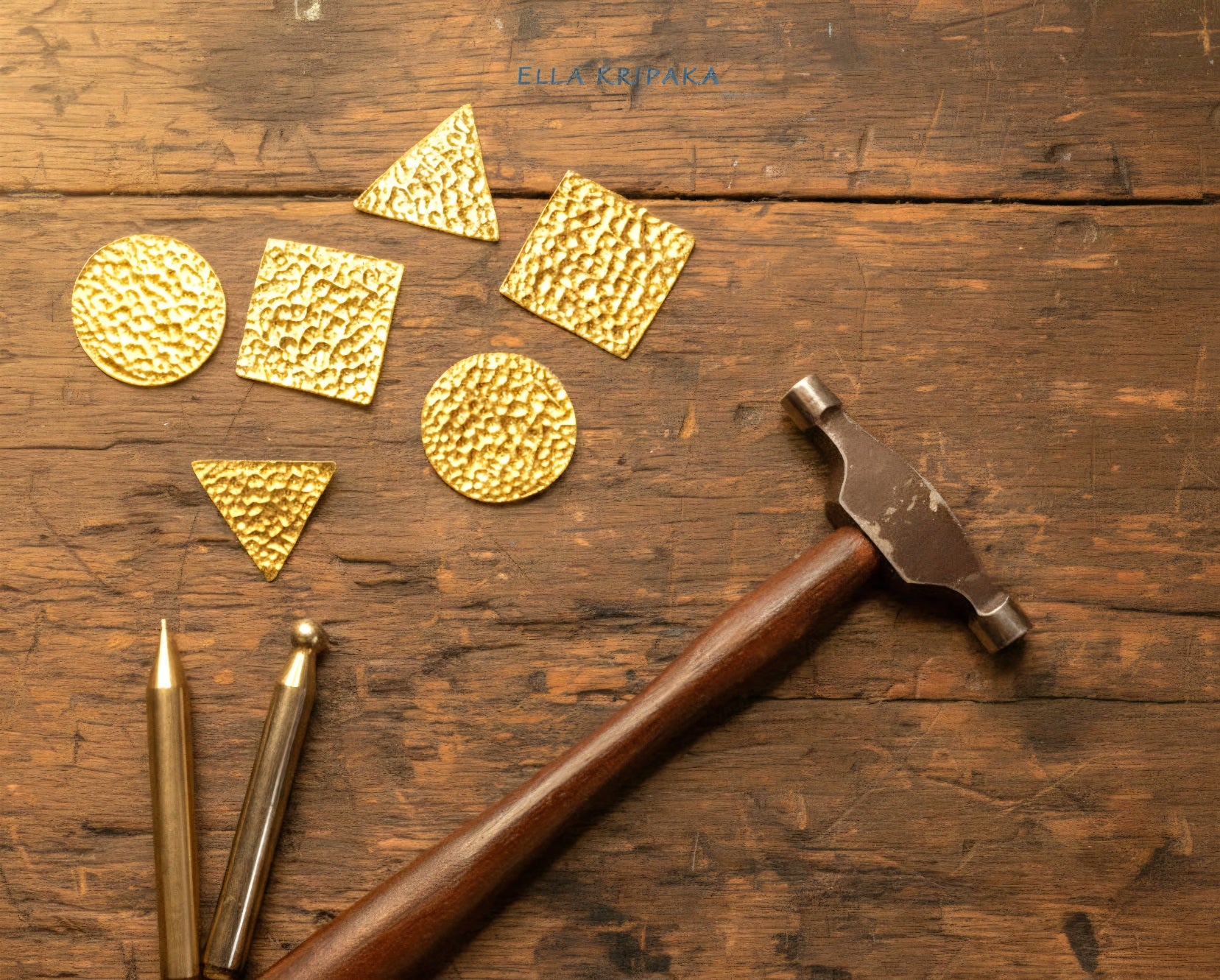 Hammered Gold jewelry pieces and jewelry tools and jewelry hammer on old rustic wooden surface with artist's name 'Ella Kripaka' branding