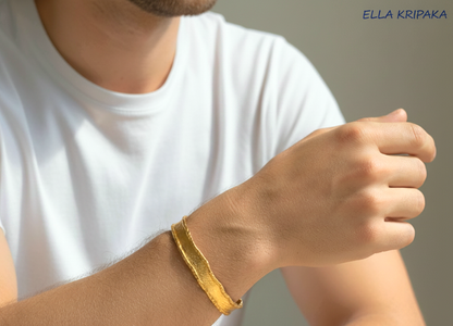 Organic Hammered 24k Gold Bangle Bracelet Textured with uneven thick edges worn on a man's hand and neutral background, branding artist-jeweler 'Ella Kripaka' 