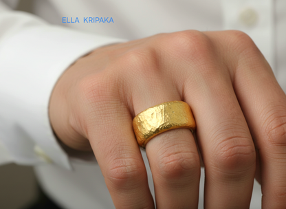 Hammered 24k Gold 9999 gold ring band thick heavy on person's finger and with textured surface on a white blurred background, branded 'Ella Kripaka'