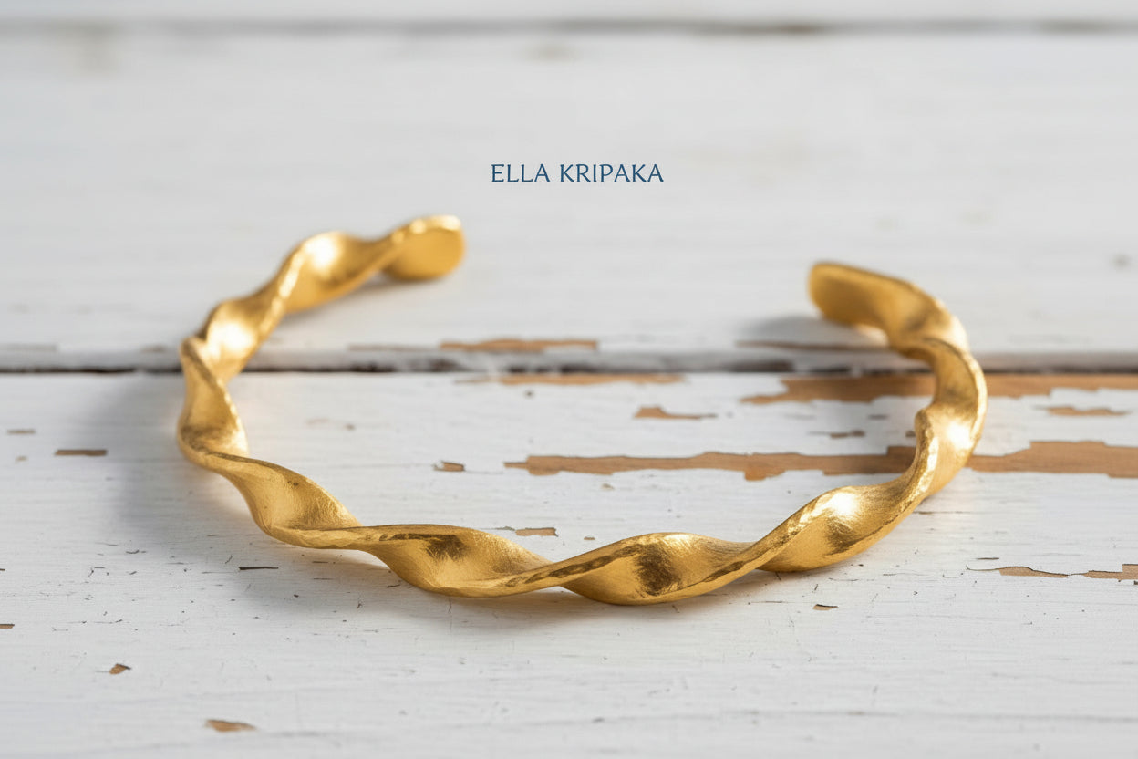Twisted Viking hammered 24k 9999 gold bracelet cuff on a old white old wooden background, branding artist-jeweler name 'Ella Kripaka'