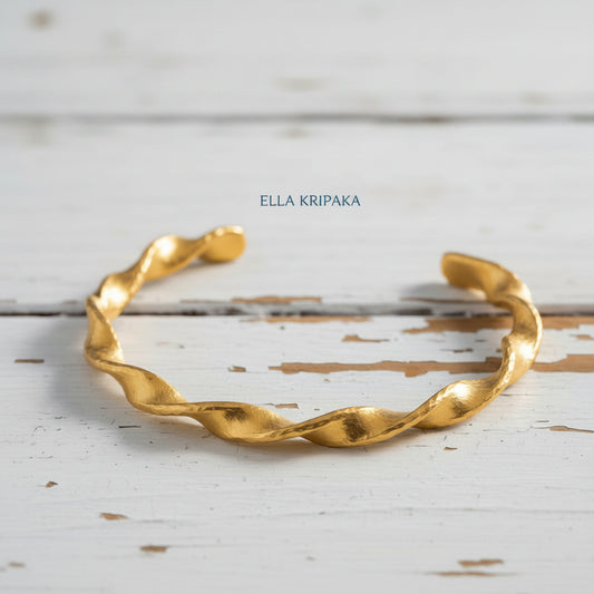 Twisted hammered 24k gold bracelet cuff on a old white wooden background, branding artist-jeweler name 'Ella Kripaka'