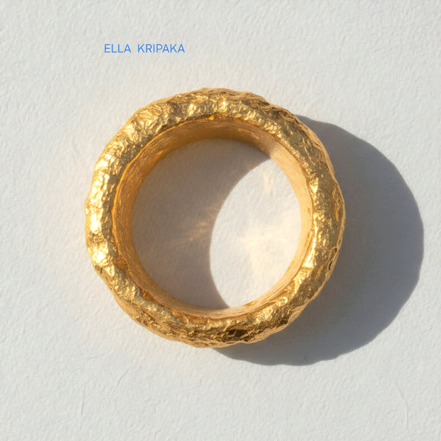 Organic hammered 24k Gold 9999 gold ring signet with thick edges and with textured surface on a white paper background, branded 'Ella Kripaka'