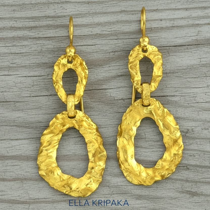 Organic hammered uneven 24k 9999 Gold earrings on a grey wooden surface, and with 'ELLA KRIPAKA' branding