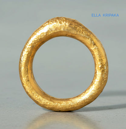 Hammered organic 24k Gold 9999 gold signet thick ring band with textured gold on a grey concrete background, branded 'Ella Kripaka'