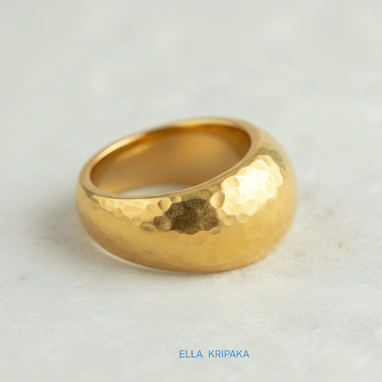Hammered 24k 9999 Gold ring convex signet Ancient Rome style on white paper surface, artist-jeweler's name 'Ella Kripaka' branding