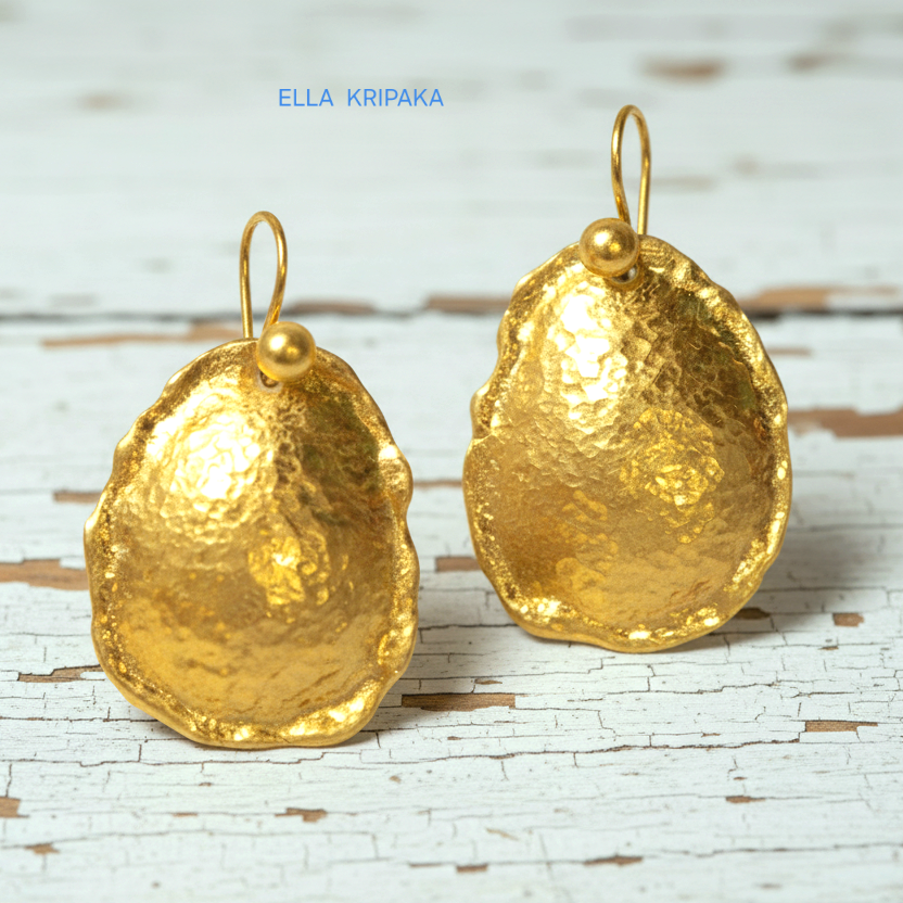 Organic 24k 9999 gold hammered convex oval earrings with thick uneven edges are on old white wooden background, artist-jeweler's name 'Ella Kripaka'