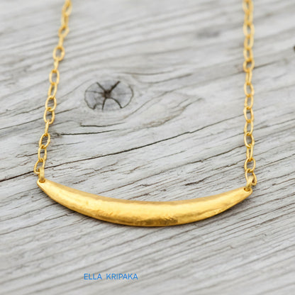 Hammered 24k gold convex Moon pendant with chain on a grey rustic wooden background with 'Ella Kripaka' branding