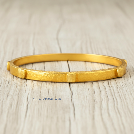 24k gold hammered bangle textured bracelet with convex squares on white rustic wooden surface, artist 'Ella Kripaka' branding