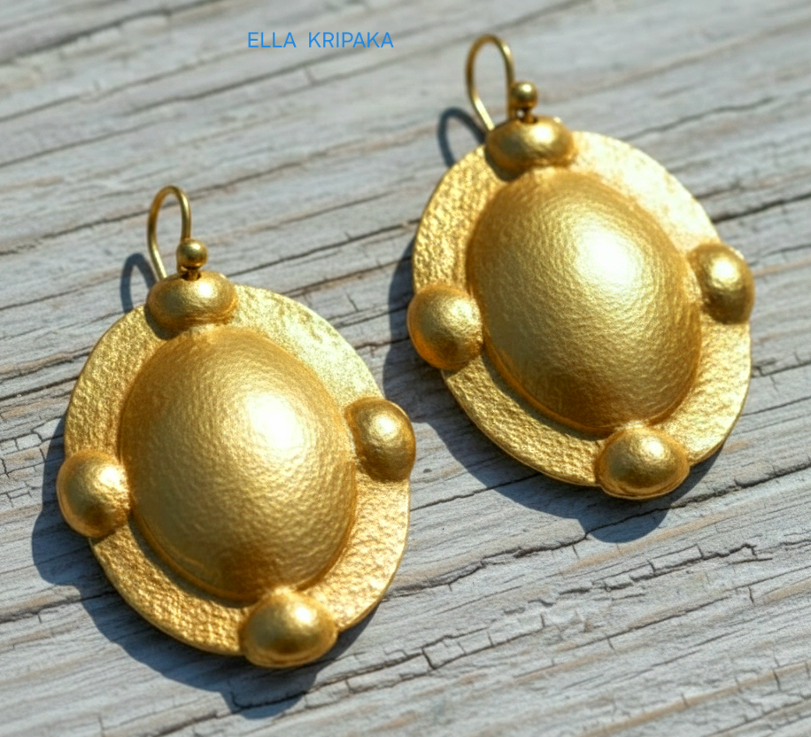 Hammered 24k gold, pure 9999 gold Byzantine convex ovals earrings with shiny forged gold textures on old wooden surface, artist-jeweler 'Ella Kripaka' branding