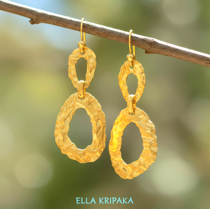 Organic hammered uneven 24k 9999 Gold earrings hanging on a branch on a blurred natural background, and with 'ELLA KRIPAKA' branding