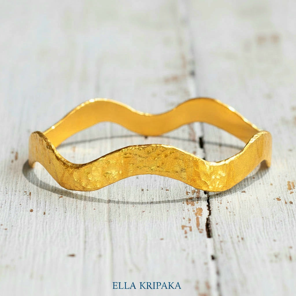 24k gold hammered bracelet textured bangle with wavy design on white rustic wooden background, branded 'Ella Kripaka'
