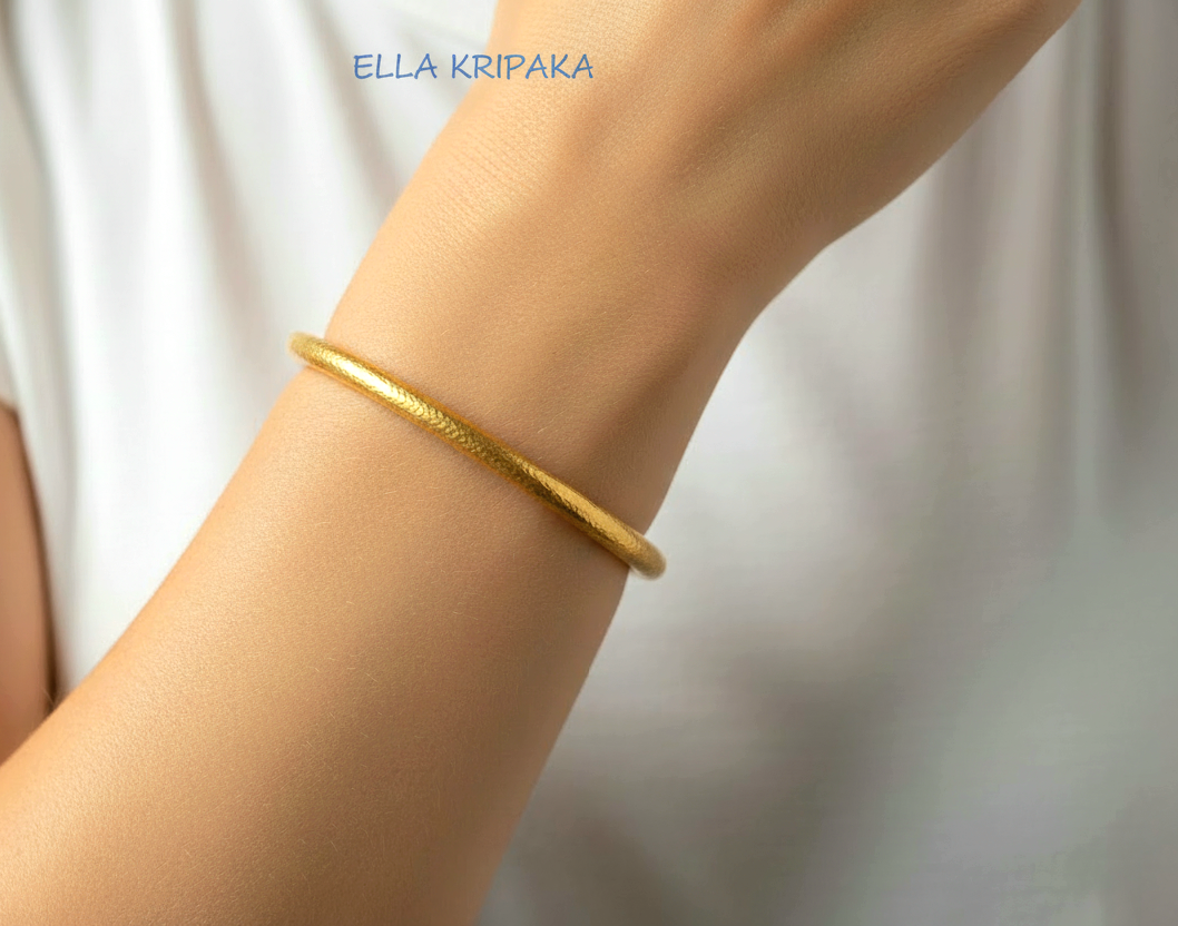 Hammered 24k 9999 gold cuff thick bracelet Ancient Rome style worn on wrist by a person and on a white t-shirt background, artist-jeweler name 'Ella Kripaka' branding