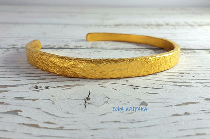 Hammered 24k 9999 gold cuff thick bracelet Ancient Rome style on old white wooden background, artist-jeweler's name 'Ella Kripaka'