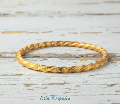 Twisted Viking Hammered 24k 9999 Gold bangle bracelet on white wooden surface, artist's name 'Ella Kripaka' branding