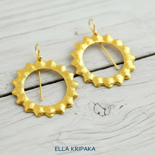 Hammered 24k Gold convex hoops Sun earrings on light grey old wooden background, and artist-jeweler's name 'Ella Kripaka' branding