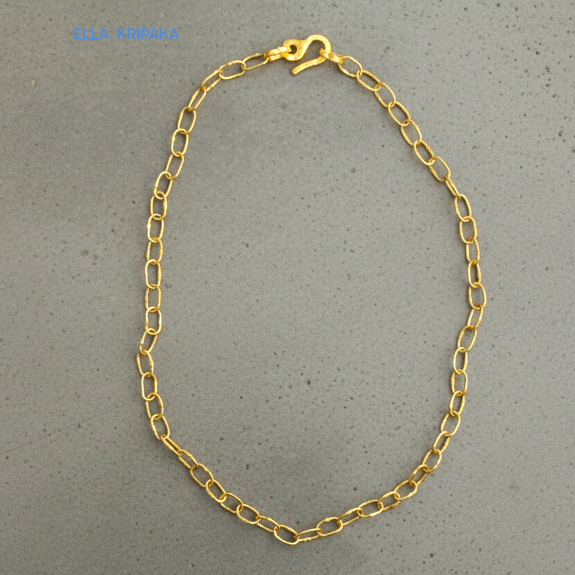 22k gold hammered chain necklace with thick hook clasp on grey concrete background, artist-jeweler's name 'Ella Kripaka' branding