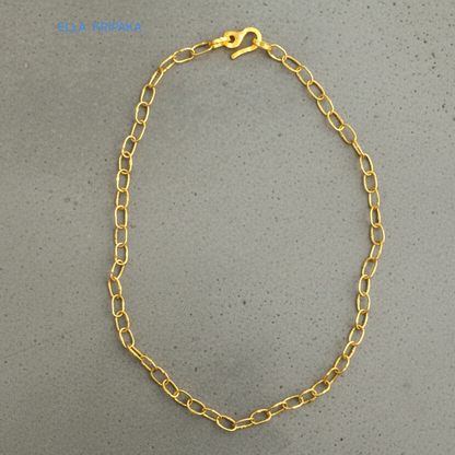 22k gold hammered chain necklace with thick hook clasp on grey concrete background, artist-jeweler's name 'Ella Kripaka' branding