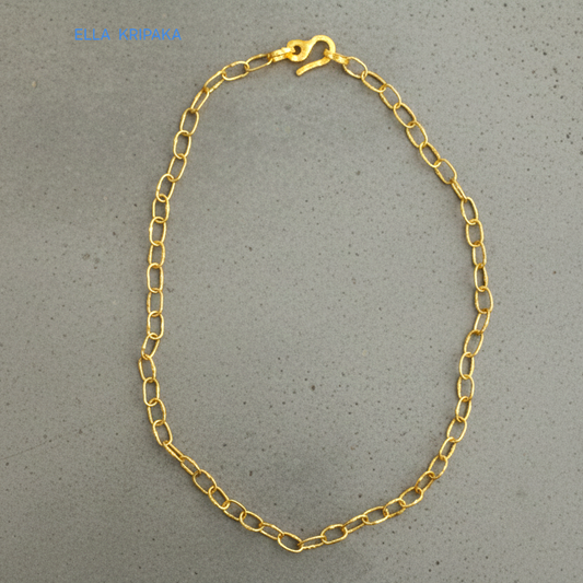 22k gold hammered chain necklace with thick hook clasp on grey concrete background, artist-jeweler's name 'Ella Kripaka' branding