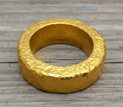 Hammered 24k 9999 Gold thick ring Ancient Rome style with a textured forged gold surface on a old wooden background, branded 'Ella Kripaka'