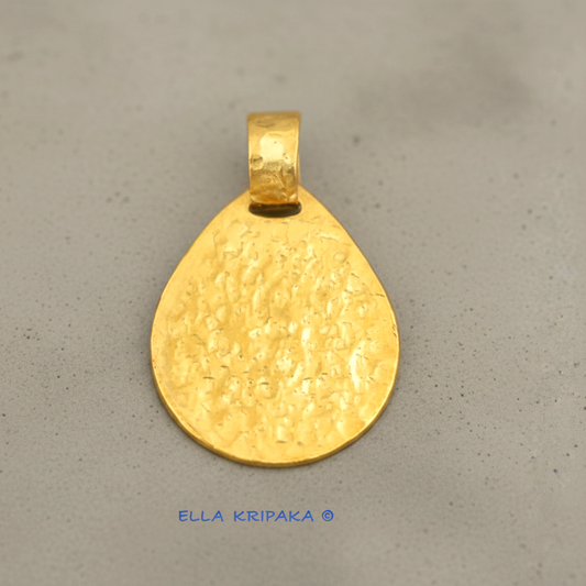 Hammered 24k gold, pure 9999 gold drop pendant with shiny forged gold textures on grey concrete surface, artist-jeweler 'Ella Kripaka' branding
