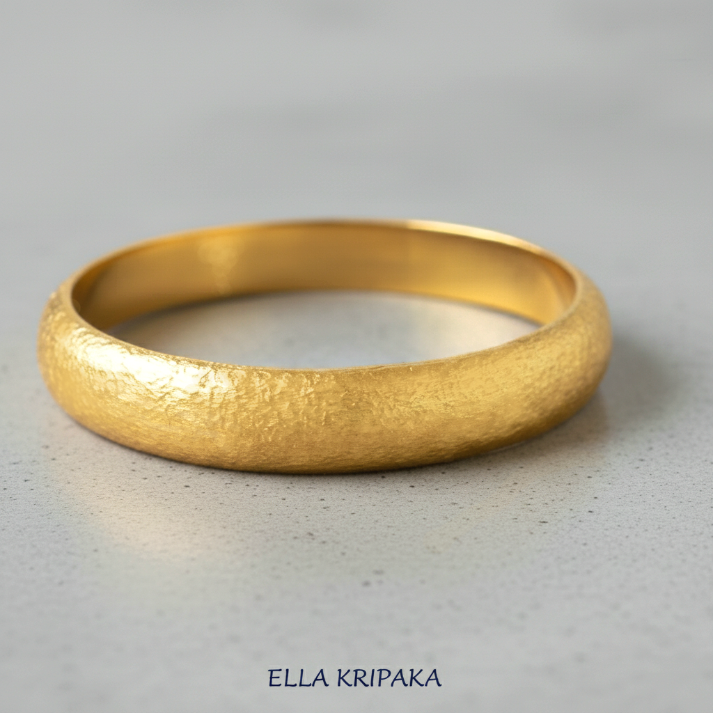 Hammered 24k gold bangle thick bracelet with rounded edges on grey polishing concrete background, and artist-jeweler 'Ella Kripaka' branding