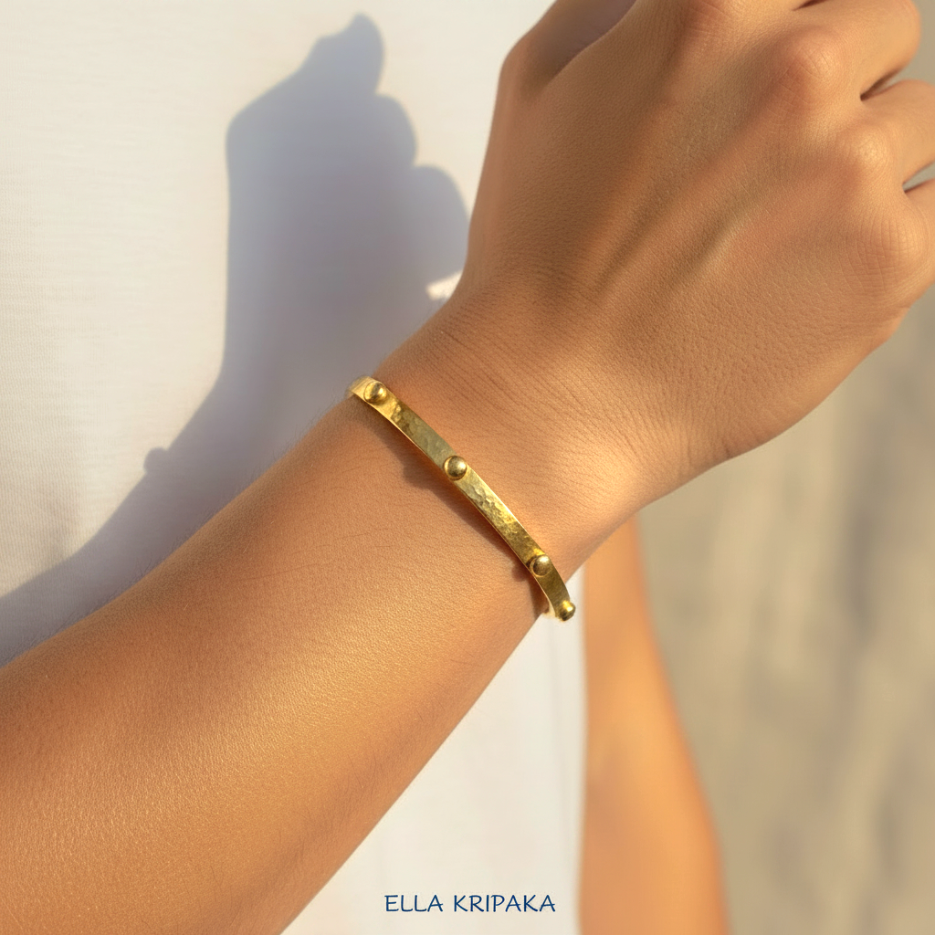 24k gold hammered cuff textured bracelet with convex rounds is worn by a man on wrist and on white t-shirt background, artist 'Ella Kripaka' branding