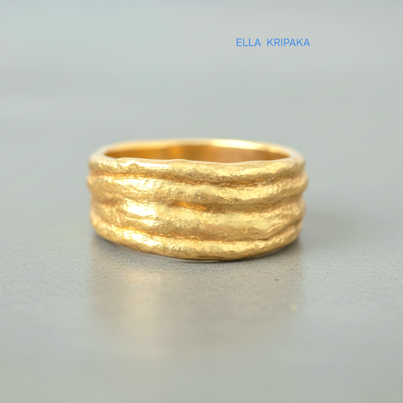Organic hammered 24k 9999 gold convex ring with uneven thick edges on grey surface, artist-jeweler's name 'Ella Kripaka' is written in picture