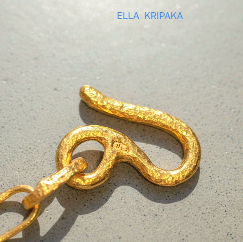 22k gold hammered chain with thick hook clasp on grey concrete background, artist-jeweler's name 'Ella Kripaka' branding