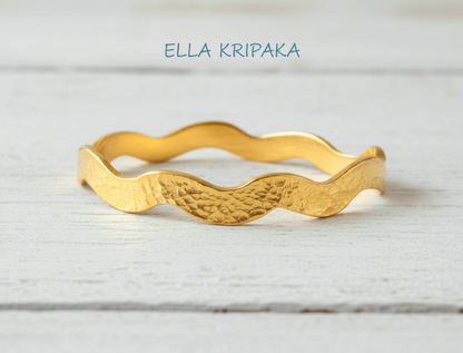 Hammered 24k 9999 Gold wavy bangle bracelet Ancient Egypt style on white wooden surface, artist's name 'Ella Kripaka' branding