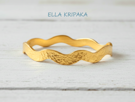 Hammered 24k 9999 Gold wavy bangle bracelet Ancient Egypt style on white wooden surface, artist's name 'Ella Kripaka' branding