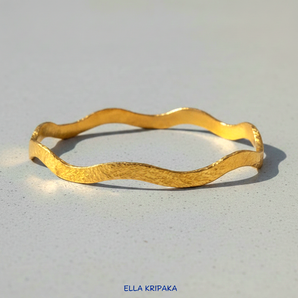 24k gold hammered bracelet bangle with wavy design on grey concrete background, branded 'Ella Kripaka'