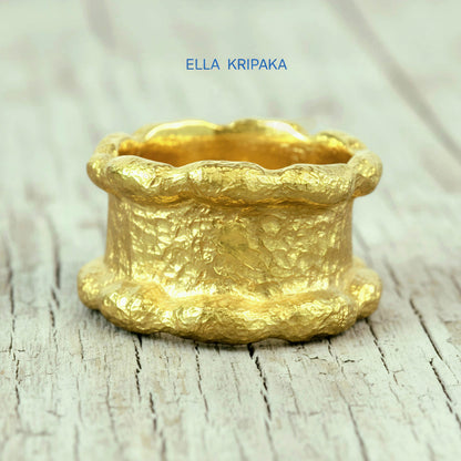 Hammered 24k 9999 Gold thick uneven wavy ring organic with a textured gold surface on a old wooden background, branded 'Ella Kripaka'