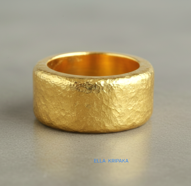 Hammered 24k Gold 9999 gold ring band thick heavy and with textured surface on a grey concrete background, branded 'Ella Kripaka'
