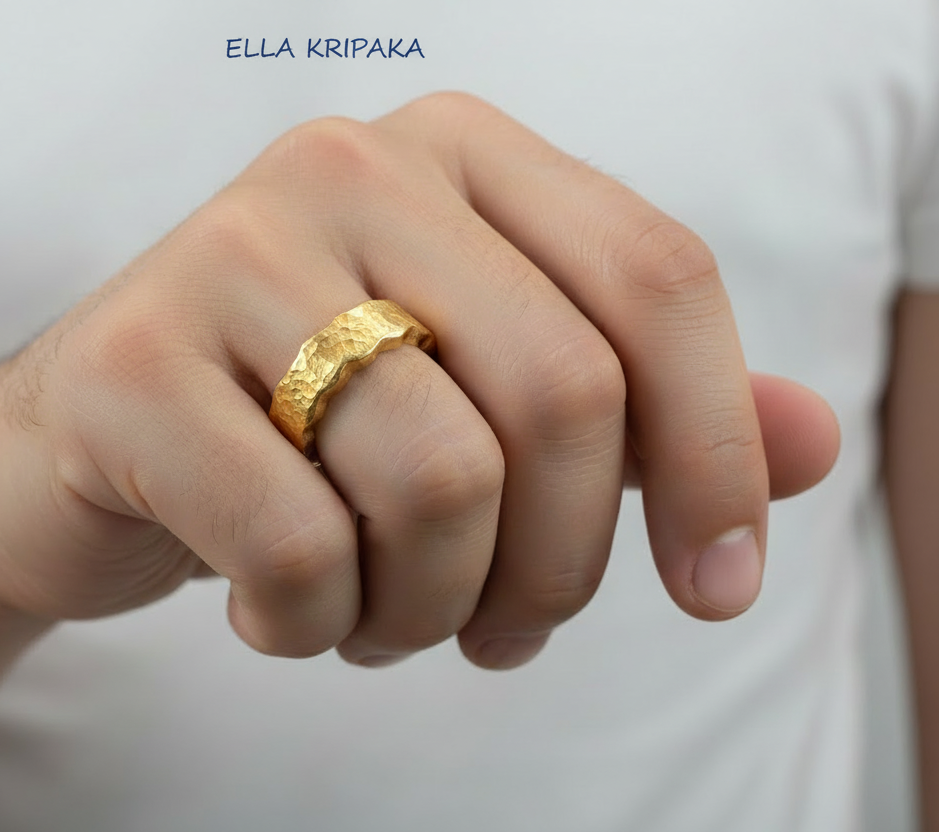 Organic hammered 24k 9999 Gold wavy ring band with thick wavy edges and with forged gold textures is worn by a man on finger and on white surface, artist-jeweler's name 'Ella Kripaka' branding