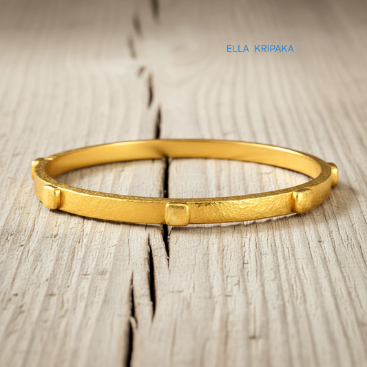 24k gold hammered bangle textured bracelet with convex squares on light rustic wooden surface, artist 'Ella Kripaka' branding