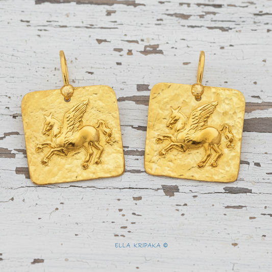 Hammered 24k Gold 9999 gold square earrings with convex Pegasus and with forged textured gold on old white wooden background, branded artist's name 'Ella Kripaka' 