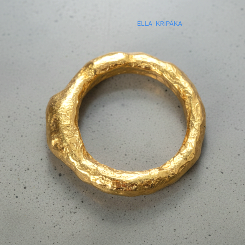 Hammered 24k 9999 Gold thick uneven ring organic signet with a textured gold surface on a grey concrete background, branded 'Ella Kripaka'