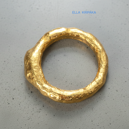 Hammered 24k 9999 Gold thick uneven ring organic signet with a textured gold surface on a grey concrete background, branded 'Ella Kripaka'