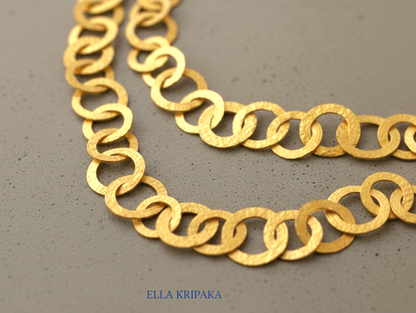 22k gold hammered chain necklace with different links on a grey concrete surface, and with 'Ella Kripaka' branding