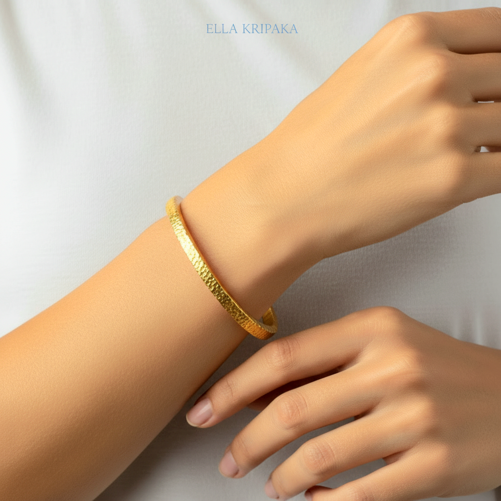 Hammered 24k 9999 gold bangle thick bracelet Ancient Rome style worn by a woman on hand and on a white background, artist-jeweler name 'Ella Kripaka'