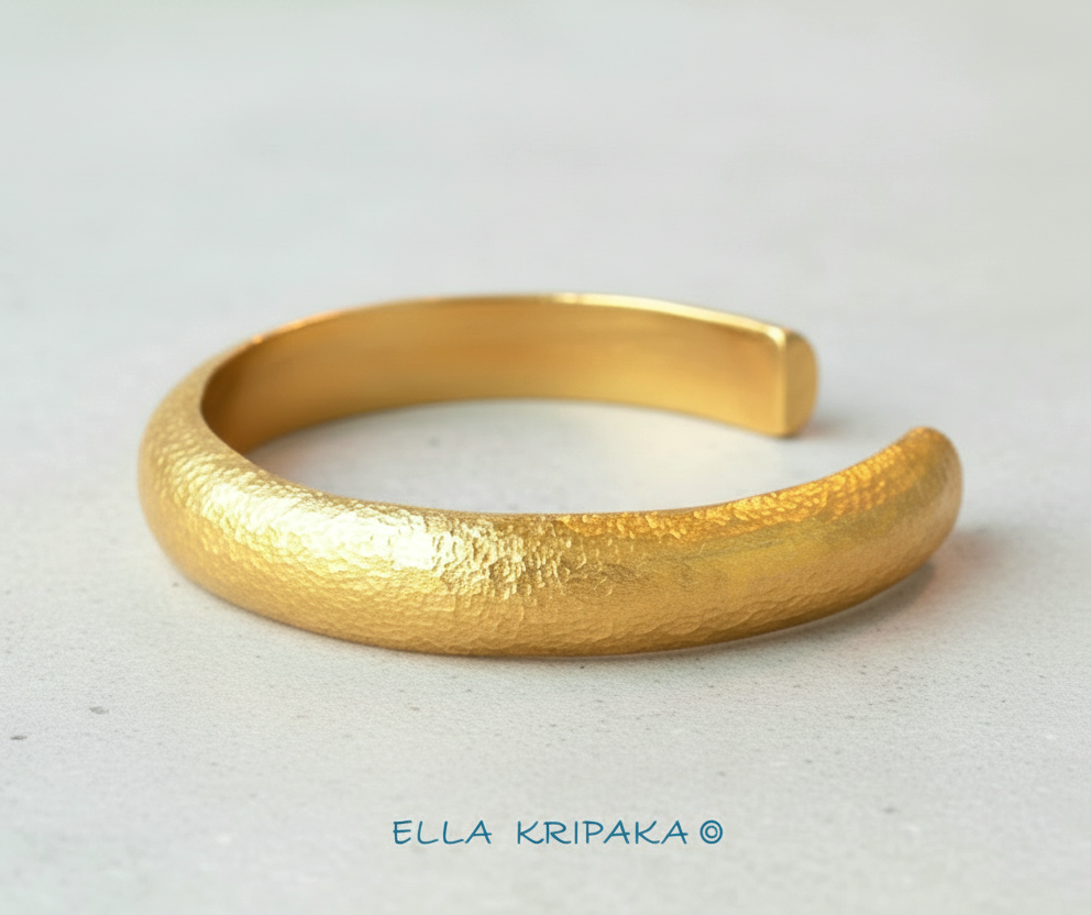 24k 9999 gold hammered cuff bracelet Ancient Rome style on a white craft paper surface, artist-jeweler 'Ella Kripaka' branding